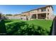 Expansive backyard with a lush green lawn and outdoor seating area on a stone patio at 1329 W Crape Rd, Queen Creek, AZ 85140