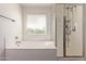 Bright bathroom features a soaking tub under a window and a separate glass-enclosed shower with shelving at 1329 W Crape Rd, Queen Creek, AZ 85140