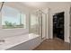 Bright bathroom with a soaking tub, glass-enclosed shower, and walk-in closet access at 1329 W Crape Rd, Queen Creek, AZ 85140