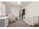This neutral carpeted bedroom has a side table, crib, dresser, and fun artwork above the dresser at 1329 W Crape Rd, Queen Creek, AZ 85140