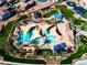 Aerial view of a vibrant community pool, featuring sunshades, lounge chairs, and lush landscaping at 1329 W Crape Rd, Queen Creek, AZ 85140