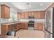Well-appointed kitchen featuring stainless steel appliances, brown cabinets, granite counters, and tile flooring at 1329 W Crape Rd, Queen Creek, AZ 85140