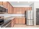 Kitchen featuring stainless steel appliances, brown cabinets, granite countertops, and tile flooring at 1329 W Crape Rd, Queen Creek, AZ 85140
