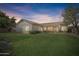 The backyard features a large grassy area and desert landscaping, set against a blue twilight sky at 14955 N 78Th Dr, Peoria, AZ 85381