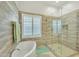 Bright bathroom features a tub next to a walk-in shower with a seamless glass door and shuttered window at 14955 N 78Th Dr, Peoria, AZ 85381