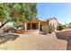 Backyard view showcasing the covered patio, desert landscaping, and mature trees at 17204 W Cordova Ct, Surprise, AZ 85387