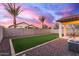 An artificial grass backyard with a patio and three palm trees overlooking the sky at 17452 W Andrea Dr, Surprise, AZ 85387