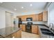 Efficient kitchen features wooden cabinets, granite countertops, black appliances and a stainless steel refrigerator at 18618 E Mockingbird Dr, Queen Creek, AZ 85142
