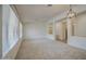 Spacious, bright living room with neutral carpet, white walls, and modern lighting with an opening to the kitchen at 18618 E Mockingbird Dr, Queen Creek, AZ 85142