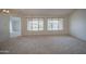 Bright, neutral living room featuring plush carpet, and large windows for natural light, and simple light fixture at 18618 E Mockingbird Dr, Queen Creek, AZ 85142