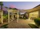 Beautiful backyard patio featuring a white pergola, brick pavers, and outdoor seating area at dusk at 18635 W Miami St, Goodyear, AZ 85338