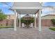 Backyard patio featuring a white pergola, pavers, and well-manicured landscaping at 18635 W Miami St, Goodyear, AZ 85338