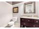Elegant half bathroom featuring a decorative mirror and a dark wood vanity cabinet at 18635 W Miami St, Goodyear, AZ 85338