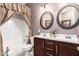 Well-lit bathroom featuring a double sink vanity, dual framed mirrors, and shower-tub combination at 18635 W Miami St, Goodyear, AZ 85338