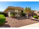 Close up side view of earth-toned home with manicured landscaping, gravel, and palm trees on a clear, sunny day at 18635 W Miami St, Goodyear, AZ 85338