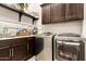 Well-lit laundry room with front-loading washer/dryer, dark cabinets, tile backsplash and countertop at 18635 W Miami St, Goodyear, AZ 85338