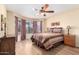 Cozy bedroom features a bed with a striped comforter, a ceiling fan, wood floors, and a bay window at 19220 N 93Rd Ave, Peoria, AZ 85382