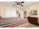 Large bedroom features wood floors, a bed with a striped comforter, a ceiling fan, and built in closet at 19220 N 93Rd Ave, Peoria, AZ 85382