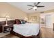 Bedroom features a white comforter bed with a ceiling fan, wood floors, and a view into the en suite bathroom at 19220 N 93Rd Ave, Peoria, AZ 85382