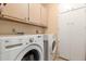 Functional laundry room with front-load washer and dryer, complemented by ample cabinet space at 19220 N 93Rd Ave, Peoria, AZ 85382