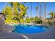 Community pool with lounge chairs surrounded by lush greenery and palm trees under a clear blue sky at 19220 N 93Rd Ave, Peoria, AZ 85382