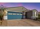 Charming single-story home with a blue garage door, brick driveway, and well-maintained landscaping at 19924 W Rancho Dr, Litchfield Park, AZ 85340
