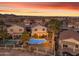 Gorgeous aerial of home with pool, desert landscaping, and view of neighborhood, all under colorful sunset at 22491 W Woodlands Ave, Buckeye, AZ 85326