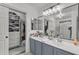 Well-lit bathroom featuring double sinks, mirrors, vanity lighting, and walk-in closet with shelving at 22491 W Woodlands Ave, Buckeye, AZ 85326