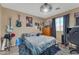 Well-lit bedroom featuring window, modern ceiling fan, guitars and posters on walls at 22491 W Woodlands Ave, Buckeye, AZ 85326