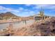 Desert landscape surrounds the home's backyard, enclosed by black fencing, on a sunny day with blue skies at 27145 N 147Th Ave, Surprise, AZ 85387
