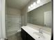 Bathroom featuring dark cabinets, a white quartz countertop, and a shower-tub combo at 36638 W Santa Clara Ave, Maricopa, AZ 85138