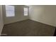A well-lit bedroom with plush carpeting, blinds, and two windows offering natural light at 36638 W Santa Clara Ave, Maricopa, AZ 85138