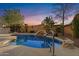 Backyard pool area with rock features and desert landscaping, illuminated by an early evening sky at 42047 N Moss Springs Rd, Anthem, AZ 85086