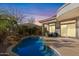 Backyard pool area with rock waterfall and desert landscaping, illuminated by an early evening sky at 42047 N Moss Springs Rd, Anthem, AZ 85086