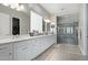 A spa-like bathroom featuring double sinks, white cabinets, and a glass-enclosed shower at 5189 N 206Th Dr, Buckeye, AZ 85396