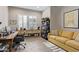 Home office with wooden desk, yellow sofa, shelving unit and natural lighting at 5189 N 206Th Dr, Buckeye, AZ 85396