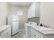 Bright laundry room featuring white cabinets, granite countertop, sink, washer and dryer, and refrigerator at 5189 N 206Th Dr, Buckeye, AZ 85396