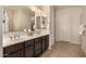 Well-lit bathroom featuring double vanity sinks, mirrors, modern hardware, and tile flooring at 7576 W Quail Ave, Glendale, AZ 85308