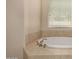 Bright bathroom featuring a tile-surround soaking tub with a window view at 7576 W Quail Ave, Glendale, AZ 85308