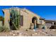Close-up of home's exterior highlighting desert landscaping, an arched entry, and a brown wooden shutter at 7576 W Quail Ave, Glendale, AZ 85308