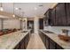 Gourmet kitchen with dark wood cabinets, granite countertops, stainless appliances, and a large island with seating at 7576 W Quail Ave, Glendale, AZ 85308
