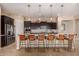 Spacious kitchen with dark cabinets, granite countertops, large island with seating, and stainless steel appliances at 7576 W Quail Ave, Glendale, AZ 85308