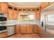 Well-lit kitchen boasts wood cabinets, stainless steel appliances, mosaic backsplash, and a view of the outdoors at 9121 W Quail W Trl, Queen Creek, AZ 85144