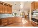 Open kitchen with custom wood cabinets, granite countertops, mosaic backsplash, and seamless flow to living area at 9121 W Quail W Trl, Queen Creek, AZ 85144