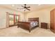 Bright main bedroom with wood-style bed frame, plush carpet, and access to the outdoors at 9121 W Quail W Trl, Queen Creek, AZ 85144
