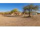 Ranch-style property featuring a house, outbuildings, and rustic fencing, with a mountain backdrop at 9121 W Quail W Trl, Queen Creek, AZ 85144