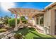 Serene backyard patio features a pergola-covered seating area with lush landscaping and a tranquil water feature at 10031 E Nacoma Ct, Sun Lakes, AZ 85248