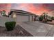 An exterior view shows a three car garage and desert landscaping at 10031 E Nacoma Ct, Sun Lakes, AZ 85248