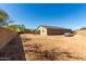 Vast backyard with beige home and car parked on the sand-covered ground, all enclosed by a tall fence at 101 W Seven Seas Dr, Casa Grande, AZ 85122