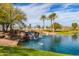 Community pond with charming rock waterfall, palm trees and grassy banks, creating a peaceful retreat for residents at 101 W Seven Seas Dr, Casa Grande, AZ 85122